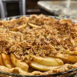 ['Close-up view of a golden-brown apple crisp pie with a flaky crust and visible apple slices.', 'Side view of a freshly baked apple crisp pie, showcasing its crunchy topping and juicy filling.', 'Delicious apple crisp pie on a plate, highlighting the crust and apple layers.', 'Appetizing image of a homemade apple crisp pie, with a textured topping and glistening apple slices.']