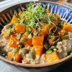 ['A close-up of a bowl of savory oatmeal topped with vibrant butternut squash and green onions.', 'A side view of creamy oatmeal with golden squash cubes and sprinkled pumpkin seeds.', 'A detailed shot of savory oatmeal garnished with microgreens and a lime wedge.', 'A colorful bowl of oatmeal featuring chunks of squash, green onions, and pumpkin seeds.']