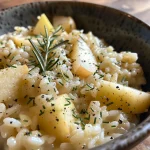 ['A close-up view of creamy Apple Risotto with grated apples and herbs.', 'Side view of a bowl filled with steaming Apple Risotto topped with grated cheese.', 'Delicious Apple Risotto presented in a bowl with visible apple pieces and garnished with rosemary.', 'Silky Apple Risotto in a dish, showcasing the rich texture and fresh ingredients.']