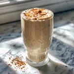 ['A close-up side view of a creamy Vanilla Chai Smoothie in a glass.', 'A refreshing Vanilla Chai Smoothie topped with spices, shown from the side.', 'A delicious Vanilla Chai Smoothie featuring a vibrant yellow hue in a clear glass.', 'A side view of a Vanilla Chai Smoothie with a straw, garnished with cinnamon.']
