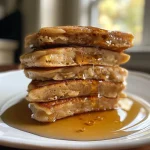 ['Close-up view of golden-brown vegan vanilla chai spiced pancakes stacked on a white plate.', 'Side view of fluffy vegan pancakes with visible chai spice and vanilla notes, served with syrup.', 'Mouthwatering vegan pancakes topped with a drizzle of maple syrup and a sprinkle of spices.', 'Juicy vegan vanilla chai pancakes arranged beautifully, showcasing their rich texture and color.']