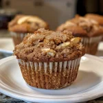 ['Close-up of golden-brown Apple Cinnamon Muffins with visible apple pieces and a crumbly top.', 'A delicious side view of freshly baked Apple Cinnamon Muffins, showcasing their fluffy texture and cinnamon dusting.', 'Juicy Apple Cinnamon Muffins displayed on a plate, highlighting their moist interior and shiny crust.', 'A tempting perspective of Apple Cinnamon Muffins, revealing chunks of apple and a sprinkle of cinnamon sugar on top.']