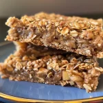 ['Close-up view of apple cinnamon oat bars displayed on a wooden table.', 'Side shot of homemade apple cinnamon oat bars showcasing texture and ingredients.', 'Delicious apple cinnamon oat bars arranged neatly, highlighting diced apples.', 'Juicy apple cinnamon oat bars with a golden-brown topping, photographed from the side.']