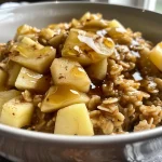 ['Close-up view of a bowl of apple cinnamon oatmeal topped with diced apples and cinnamon.', 'Side view of creamy oatmeal with apples and a sprinkle of cinnamon in a rustic bowl.', 'Appetizing shot of apple cinnamon oatmeal featuring honey crisp apples and a drizzle of maple syrup.', 'Textured bowl of warm oatmeal with visible apple chunks and a dusting of cinnamon.']