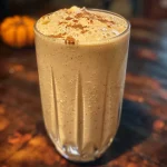 ['Close-up view of a creamy Chai Smoothie in a glass with a straw.', 'Side angle of a Chai Smoothie topped with a sprinkle of spices.', 'Chai Smoothie in a clear glass, showcasing its rich, golden-brown color.', 'Delicious-looking Chai Smoothie with ingredients visible in the background.']