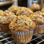 ['A close-up side view of a golden brown muffin, highlighting its moist texture and apple pieces.', 'Juicy Golden Harvest Muffins with a textured surface, showcasing shredded apples and nuts.', 'Side profile of a freshly baked muffin, warm and inviting, with visible carrots and coconut.', 'A delicious muffin revealing its golden crust, featuring bits of fruit and a wholesome appearance.']