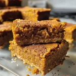 ['Close-up view of healthy pumpkin bars with chocolate chips, showcasing a delectable texture.', 'Side view of moist pumpkin bars topped with dark chocolate, highlighting their rich color.', 'Healthy pumpkin bars displayed on a wooden surface, emphasizing their soft and inviting appearance.', 'Juicy pumpkin bars with a hint of chocolate, captured in a vibrant and appetizing manner.']