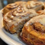 ['Close-up of golden-brown pumpkin cinnamon rolls drizzled with glaze.', 'Side view of healthy pumpkin cinnamon rolls showcasing a fluffy texture.', 'Warm pumpkin cinnamon rolls with cinnamon dusting and melted butter.', 'Detailed view of soft, spiraled pumpkin cinnamon rolls on a rustic plate.']