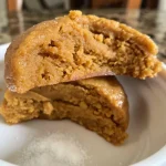 ['Close-up view of creamy pumpkin cookie dough in a bowl, topped with flaky sea salt.', 'Side angle of delicious pumpkin cookie dough, showcasing its rich texture and vibrant color.', 'High-quality image of edible pumpkin cookie dough with visible ingredients like almond butter and spices.', 'Spoonful of high protein pumpkin cookie dough, highlighting its smooth consistency and tasty toppings.']