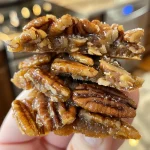 ['Close-up of golden brown Keto Pecan Pralines on a white plate, showcasing their glossy texture.', 'Side view of freshly made Keto Pecan Pralines with pecan pieces visible, glistening in natural light.', 'A detailed look at Keto Pecan Pralines, highlighting the buttery caramel coating and toasted pecans.', 'Close-up image of Keto Pecan Pralines, emphasizing the rich color and texture of the confection.']