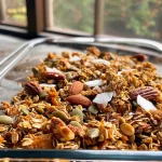 ['Close-up side view of a bowl of Maple Pumpkin Granola with visible pecans and coconut flakes.', 'Juicy maple pumpkin granola featuring oats, pumpkin seeds, and spices in a textured arrangement.', 'A hearty mix of granola with pumpkin puree, coconut flakes, and nuts captured in a detailed side view.', 'Detailed photo showing a colorful assortment of Maple Pumpkin Granola with ingredients like oats and pecans.']