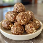 ['A close-up view of No Bake Vanilla Fig Protein Balls displayed on a wooden surface.', 'Side view of several No Bake Vanilla Fig Protein Balls made with nuts and figs.', 'A cluster of No Bake Vanilla Fig Protein Balls showcasing a chewy texture and nutty finish.', 'Delicious No Bake Vanilla Fig Protein Balls arranged neatly, highlighting their ingredients.']