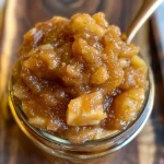 ['Close-up view of a jar filled with No Sugar Apple Butter next to fresh apples.', 'Side view of homemade No Sugar Apple Butter in a glass jar on a wooden table.', 'Delicious No Sugar Apple Butter with a spoon resting beside it, showcasing its texture.', 'A vibrant jar of No Sugar Apple Butter surrounded by whole apples and spices.']