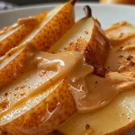 ['Close-up of a sliced pear with a creamy peanut butter yogurt dip beside it.', 'Side view of a juicy pear paired with peanut butter yogurt dip on a plate.', 'Fresh pear slices arranged next to a small bowl of peanut butter yogurt dip.', 'Juicy pear wedges served with a rich peanut butter yogurt dip in a casual setting.']