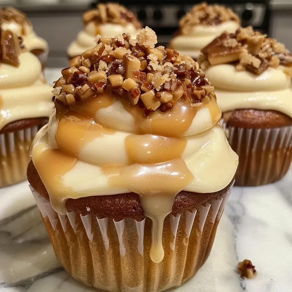 ['Close-up view of a praline cupcake topped with toffee bits and creamy frosting.', 'Side view of a delicious praline cupcake showcasing a rich, inviting swirl of frosting.', 'A scrumptious praline cupcake with a glossy finish and a sprinkle of toffee bits on top.', 'Detailed shot of a praline cupcake featuring a soft texture and a decadent frosting layer.']
