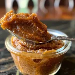 ['Close-up view of a jar filled with rich, creamy pumpkin butter.', 'Side view of pumpkin butter in a glass jar, showcasing its smooth texture.', 'A spoon scooping out luscious pumpkin butter from a jar.', 'Jars of pumpkin butter with a rustic background, emphasizing its vibrant color.']