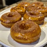 ['Close-up image of fluffy pumpkin donuts with a light glaze.', 'Side view of warm pumpkin donuts dusted with powdered sugar.', 'Juicy pumpkin donuts arranged on a rustic plate.', 'Detailed shot of glazed pumpkin donuts with hints of cinnamon.']