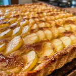 ['Close-up of a rustic apple tart with golden crust and juicy apple slices.', 'Side view of a delicious apple tart, showcasing its flaky pastry and apple filling.', 'Detailed shot of a homemade apple tart, featuring a sprinkle of cinnamon and almond powder.', 'Rustic apple tart with a glossy finish, highlighting the baked apple slices on top.']