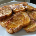 ['Close-up view of golden-brown sourdough French toast with syrup drizzle.', 'Side view of fluffy sourdough French toast topped with powdered sugar and berries.', 'Juicy slices of sourdough French toast garnished with a rich caramel sauce.', 'Delicious sourdough French toast served on a plate with a fork beside it.']