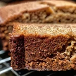 ['A close-up side view of a loaf of spiced applesauce bread with a golden-brown crust.', 'A rich, moist slice of spiced applesauce bread showcasing its texture and spices.', 'A detailed view of spiced applesauce bread, highlighting the inviting warm colors and spices.', 'A side perspective of freshly baked spiced applesauce bread, emphasizing its moist interior.']