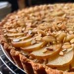 ['Close-up view of a spiced pear and almond tart showcasing its golden crust and juicy fruit filling.', 'Side view of a freshly baked spiced pear and almond tart with visible almond topping and pear slices.', 'Detailed photo of a delectable spiced pear and almond tart, highlighting the shiny, caramelized pears on top.', 'Close-up of a spiced pear and almond tart, featuring a flaky crust and slices of pear arranged beautifully.']