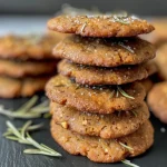['Close-up view of vegan rosemary cookies featuring chunks of honeynut squash.', 'Side view of freshly baked vegan rosemary cookies topped with sugar.', 'Juicy vegan rosemary cookies with a golden-brown exterior and herbs visible.', 'Detailed image of vegan cookies infused with rosemary and honeynut squash.']