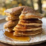 ['Close-up view of fluffy vegan vanilla chai spiced pancakes stacked on a plate.', 'A side view of beautifully plated vegan vanilla chai spiced pancakes with syrup drizzled over.', 'Juicy vegan vanilla chai spiced pancakes garnished with a sprinkle of cinnamon.', 'Delicious vegan vanilla chai spiced pancakes stacked high, showcasing their fluffy texture.']